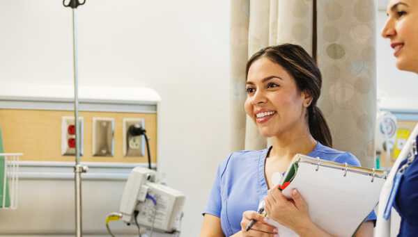 two nurses in a hospital consult with a patient