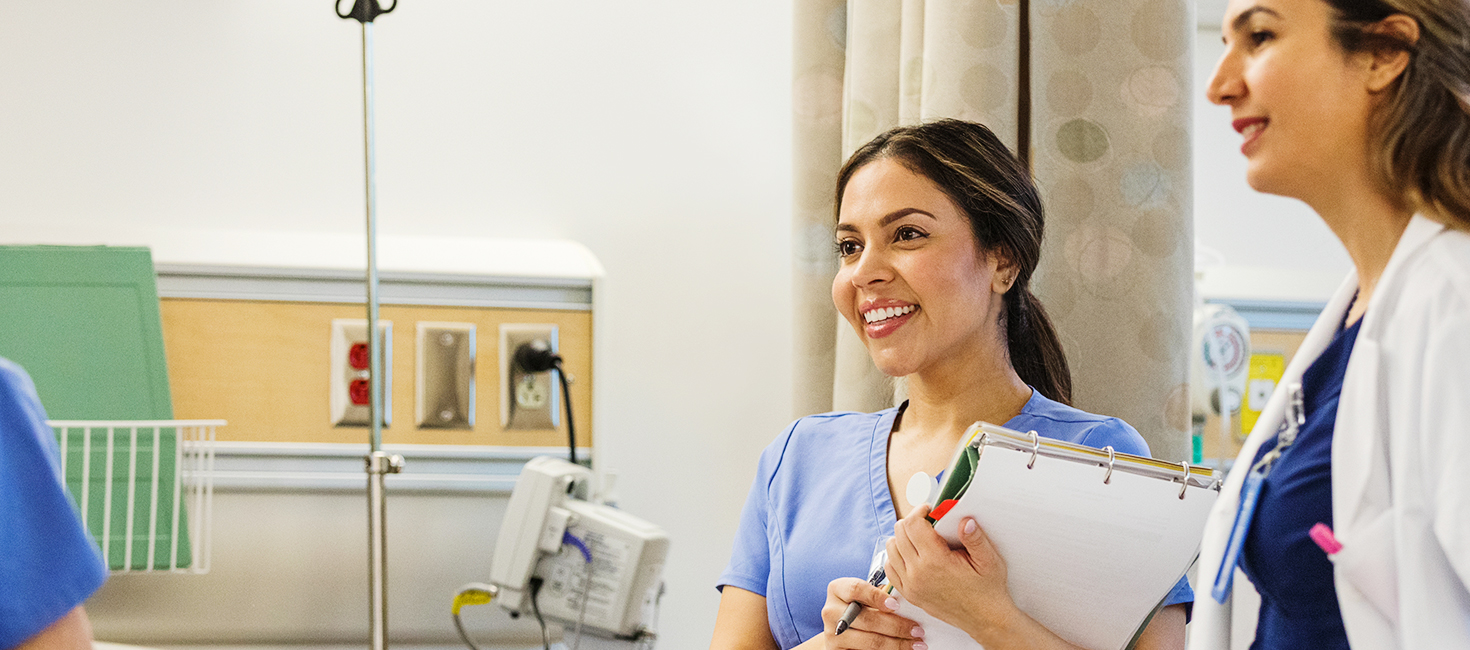 two nurses in a hospital consult with a patient