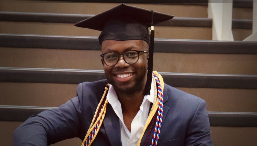 Jervaughn Miller smiling in a grad cap and honor cords
